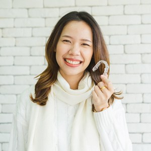 woman holding aligner smiling