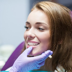 Woman smiling while dentist holds a color guide