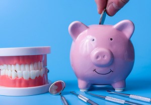 A piggy bank and various dental instruments set against a blue background