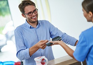 A smiling man paying for his dental visit
