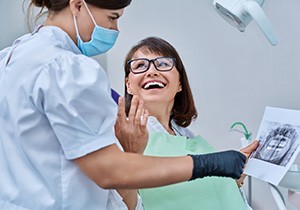 Woman smiling with dentist while reviewing X-ray