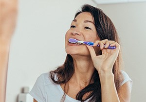 Woman brushing her teeth in bathroom