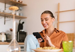 Woman smiling while looking at phone at home