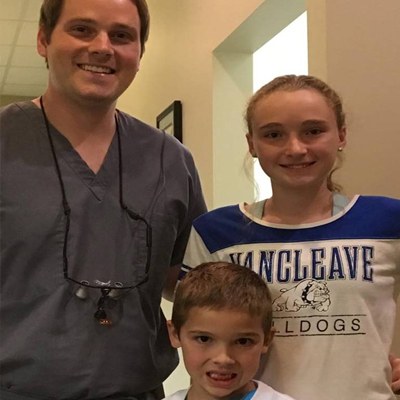 Dr. smiling with two young patients.