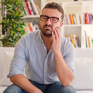 Man with a toothache in Mobile sitting on a couch