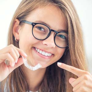 Smiling girl pointing to her Invisalign in West Mobile