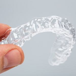 A person holding a clear aligner.