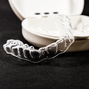 A pair of clear aligners sitting on a table and case.