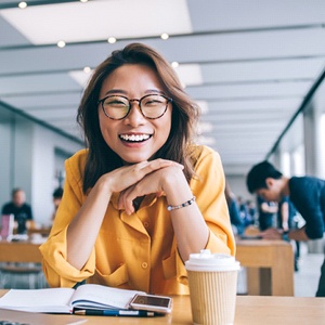 person smiling and resting their chin on their hands