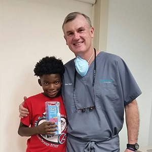 dentist with patient holding toothbrush