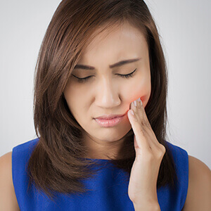 woman holding cheek in pain