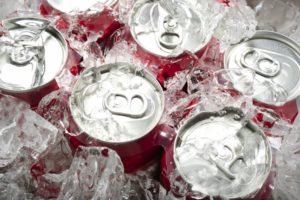 A six pack of soda underneath ice.