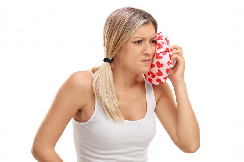 woman holding ice pack on jaw