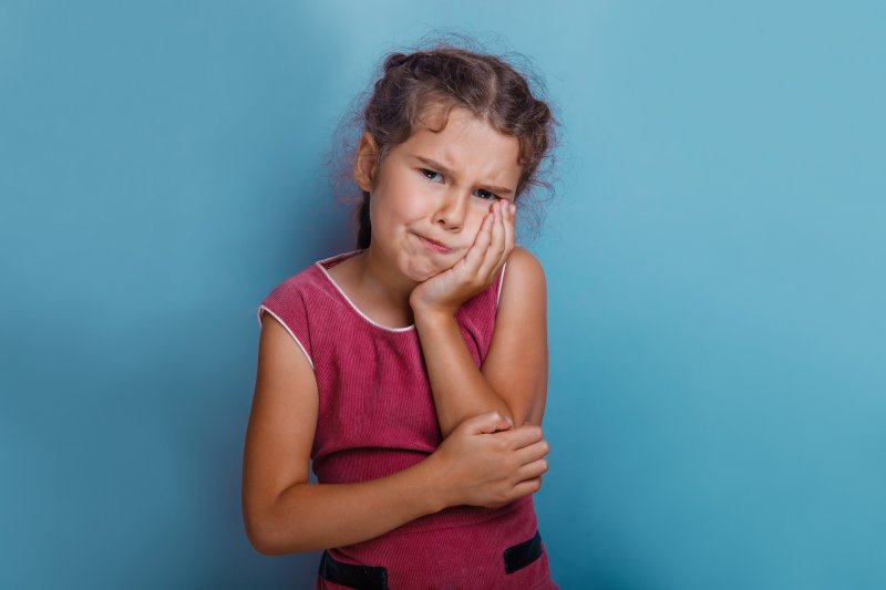 a young girl holding her cheek in pain