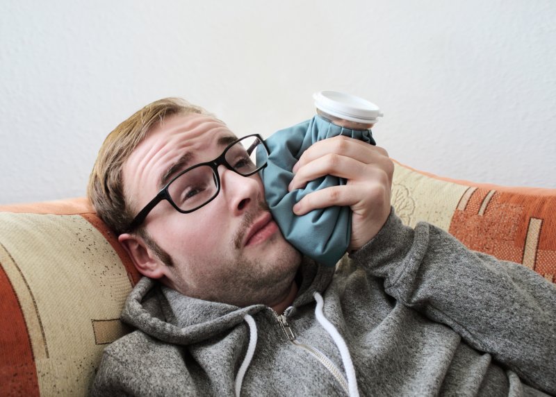 man holding icepack to jaw