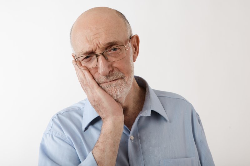 older man bald head holding jaw from tooth pain