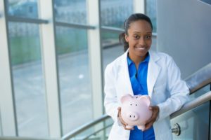 dentist in West Mobile holding pink piggy bank 