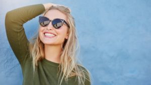 woman with sunglasses smiling after teeth whitening
