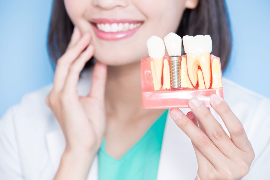 Nose-to-chest view of dentist holding sample implant touching her jaw
